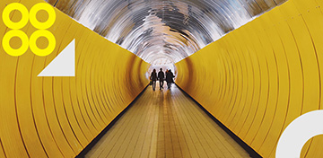 Drei Personen laufen in einem gelben Tunnel.