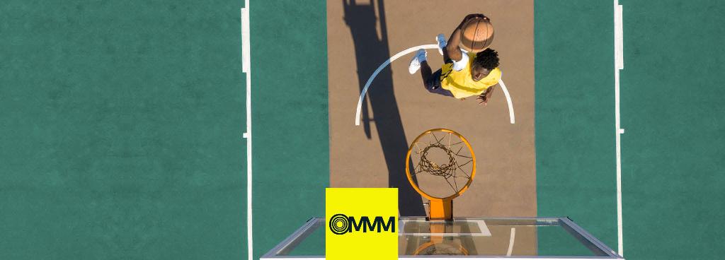 Ein Basketballspieler hält einen Ball in der Hand und setzt zu einem Dunk an.