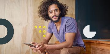 Ein junger Mann sitzt auf einer Stufe mit seinem Handy in der Hand.