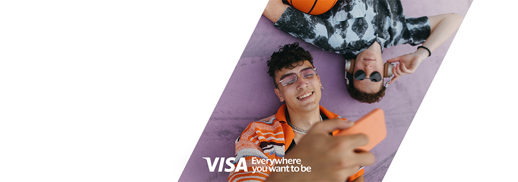 Zwei junge Männer liegen entspannt auf dem Boden. Auf dem Bild ist das Logo von Visa mit dem Zusatz „Everywhere you want to be“ platziert.