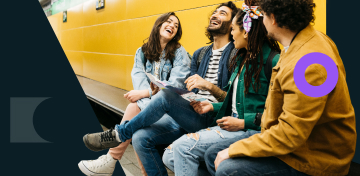 Eine lachende Gruppe junger Menschen sitzt auf einer Bank in einer U-Bahn-Station.